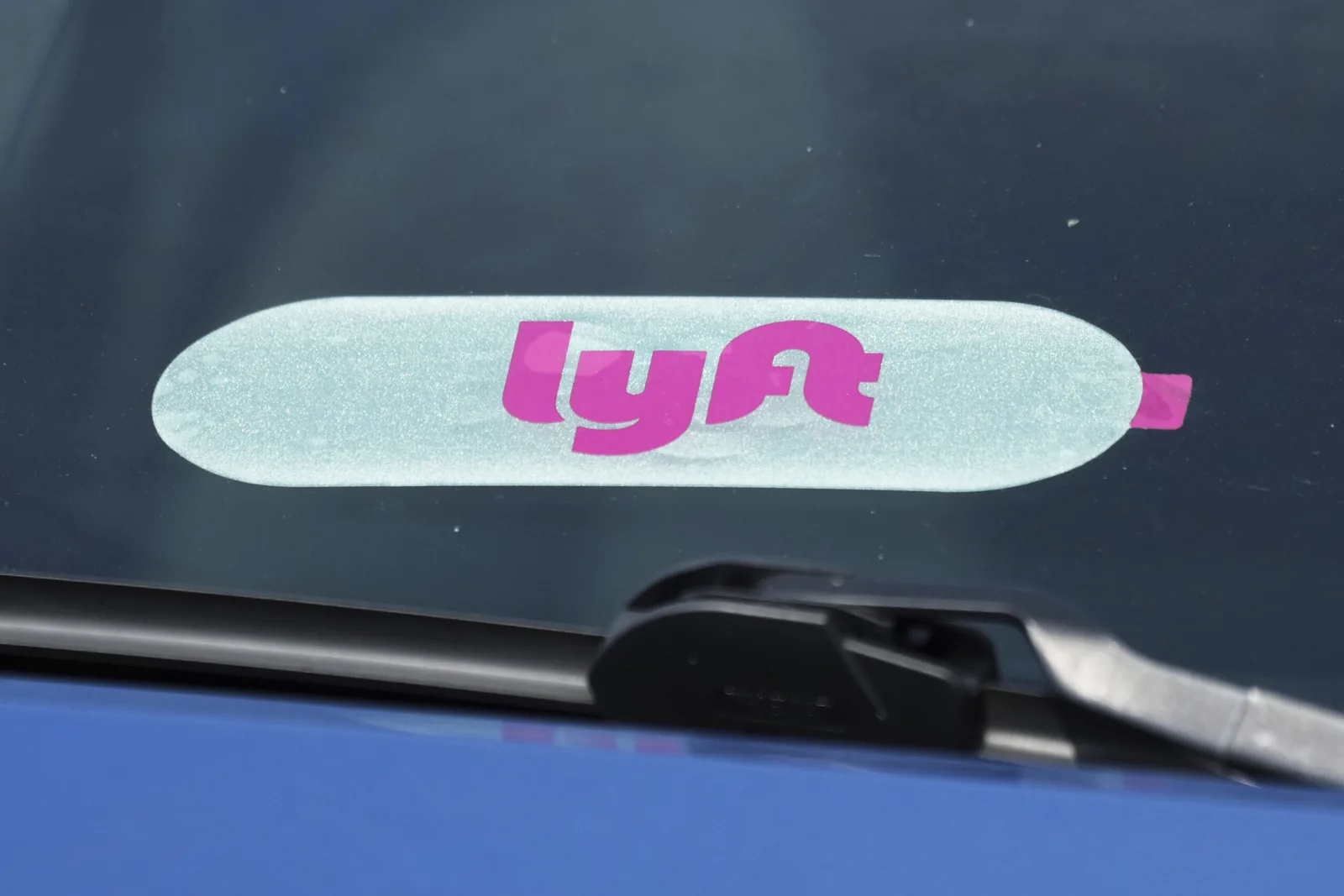 A rideshare driver waits with a phone showing a ride app in an Illinois city