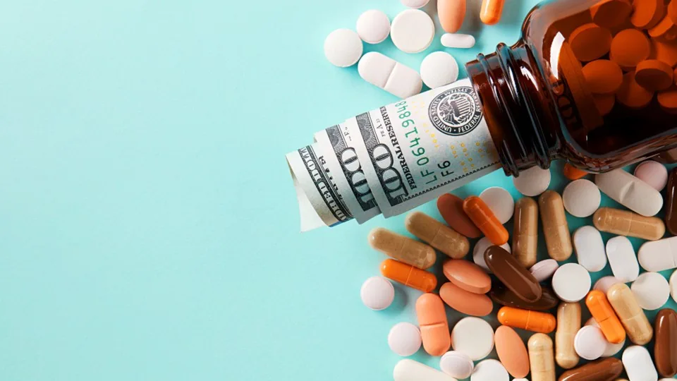 Prescription bottles and a calculator beside paperwork about drug rebates and pricing